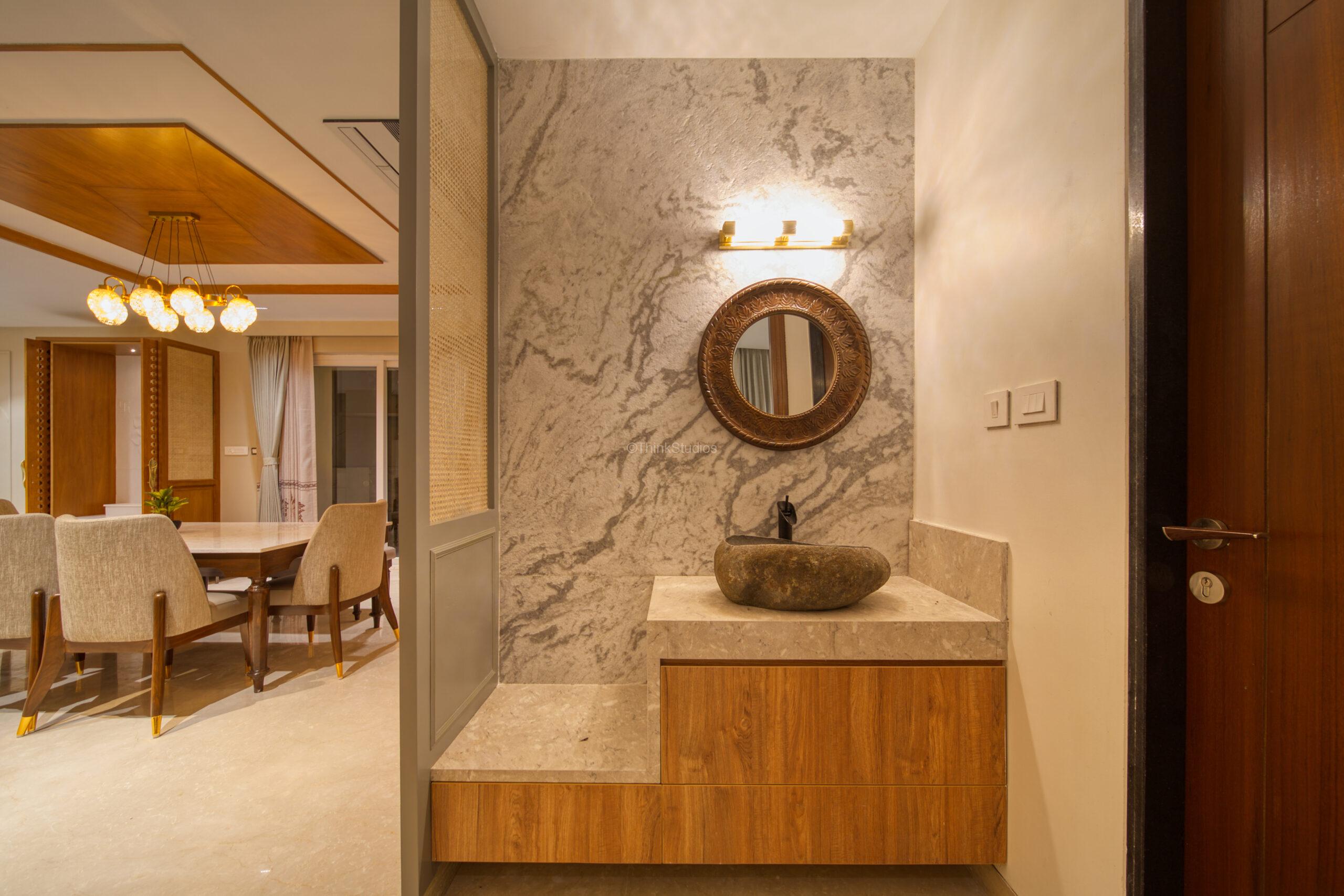 Powder room with stone cladded background, custom designed washbasin, a round decorative mirror and elegant lights